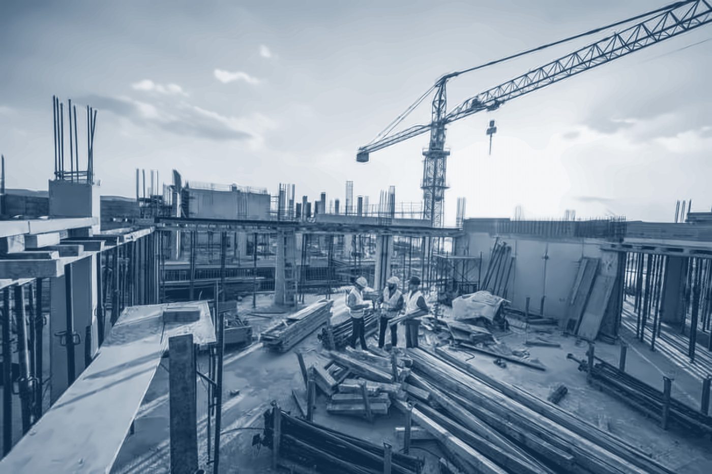 Engineers reviewing drawings on a building site under a tower crane